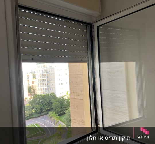 תריסים חצי סגורים בחלון פתוח עם מסגרת לבנה